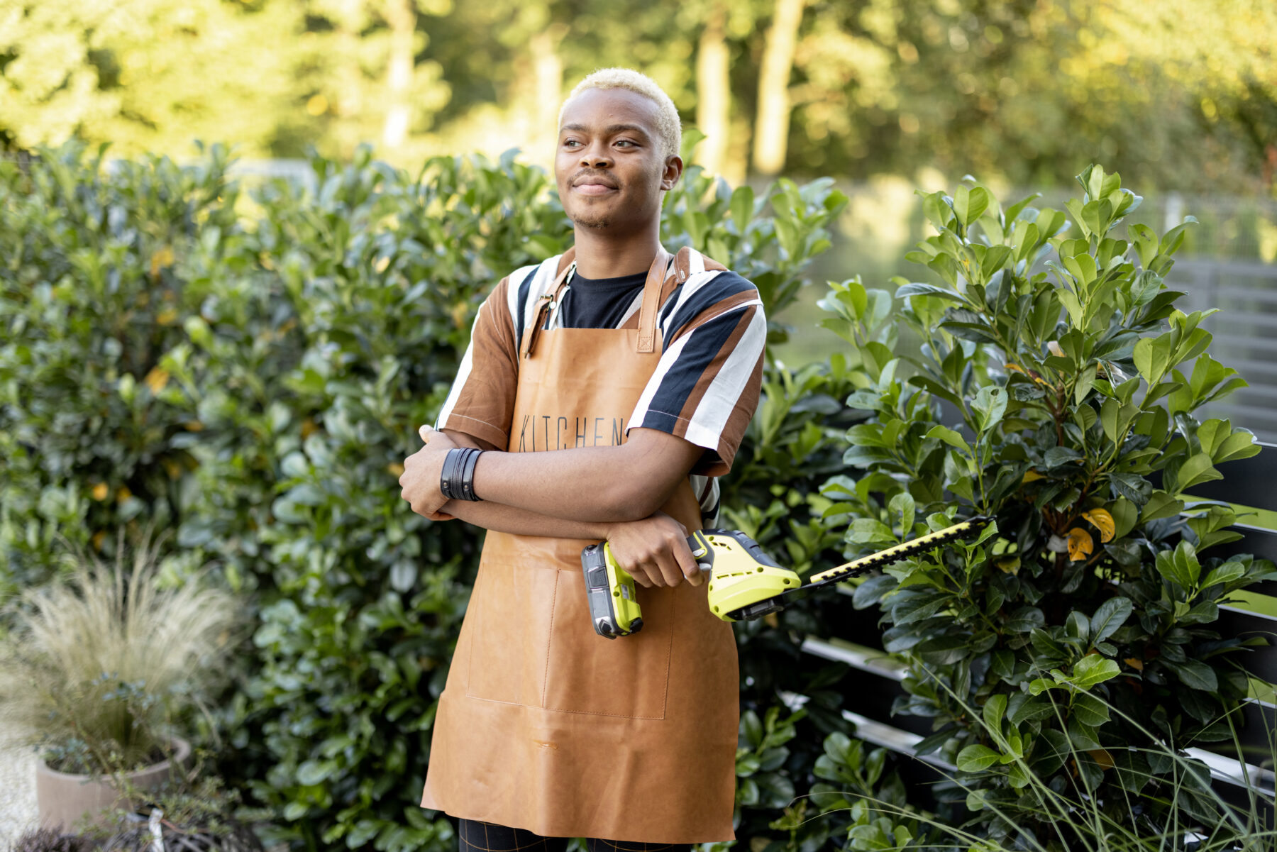 Portrait of a apprentice gardener with gardening scissors in his yard.